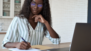 Teacher planning lessons using a laptop and notebook