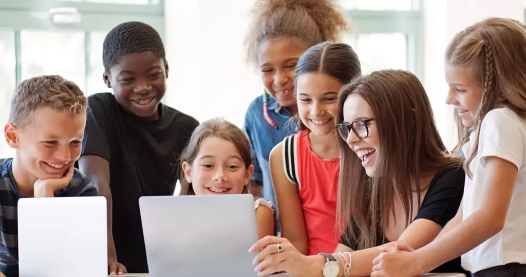 Students and Teacher Smiling at Laptop Screen Image