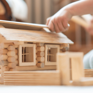 A child learns carpentry and construction skills using a wooden house toy