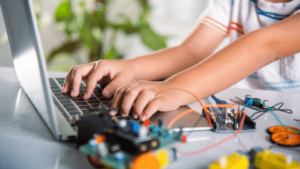 A young student studies electronics and engineering using a digital platform and a model