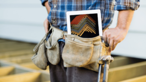 Man working in a carpentry studio, holding a tablet with VIVED Learning Carpentry Course