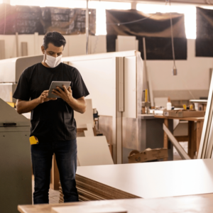 Man working in a carpentry studio, holding a tablet with VIVED Learning Carpentry Course