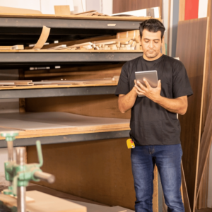 Man working in a carpentry studio, holding a tablet with VIVED Learning Carpentry Course