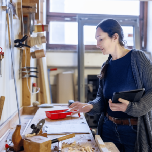 Woman working in a carpentry studio, holding a tablet with VIVED Learning Carpentry Course